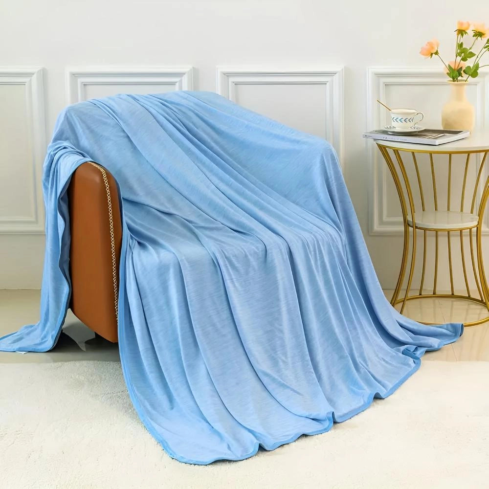 
A cooling blanket in a blue color, designed for quick cool down and temperature regulation, displayed draped over a wooden chair.