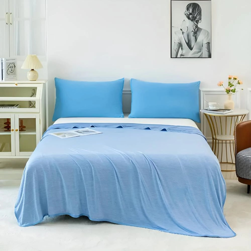 A cooling blanket in shades of azure and aqua, draped on a neatly made bed with a wooden frame, illustrating a comfortable and cool sleeping environment.