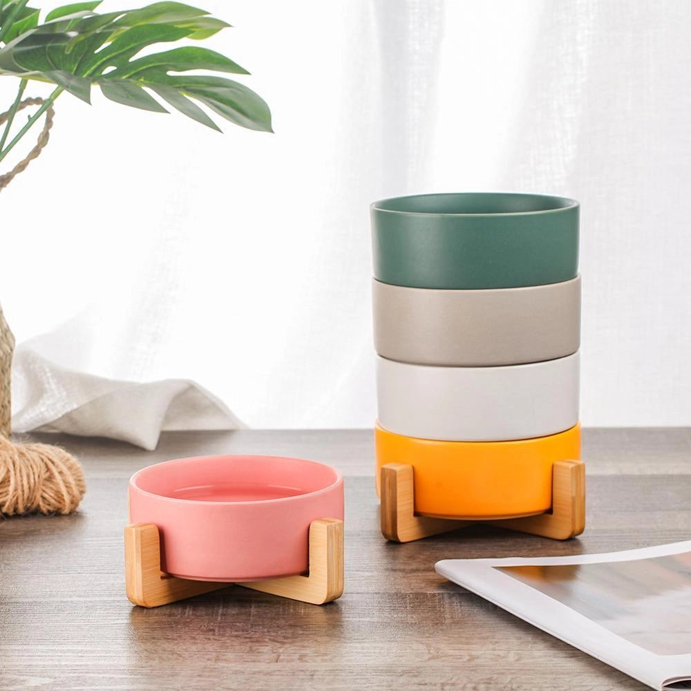 Adjustable multi-level bamboo pet feeder with colorful dishes placed on a wooden floor in a living room setting.