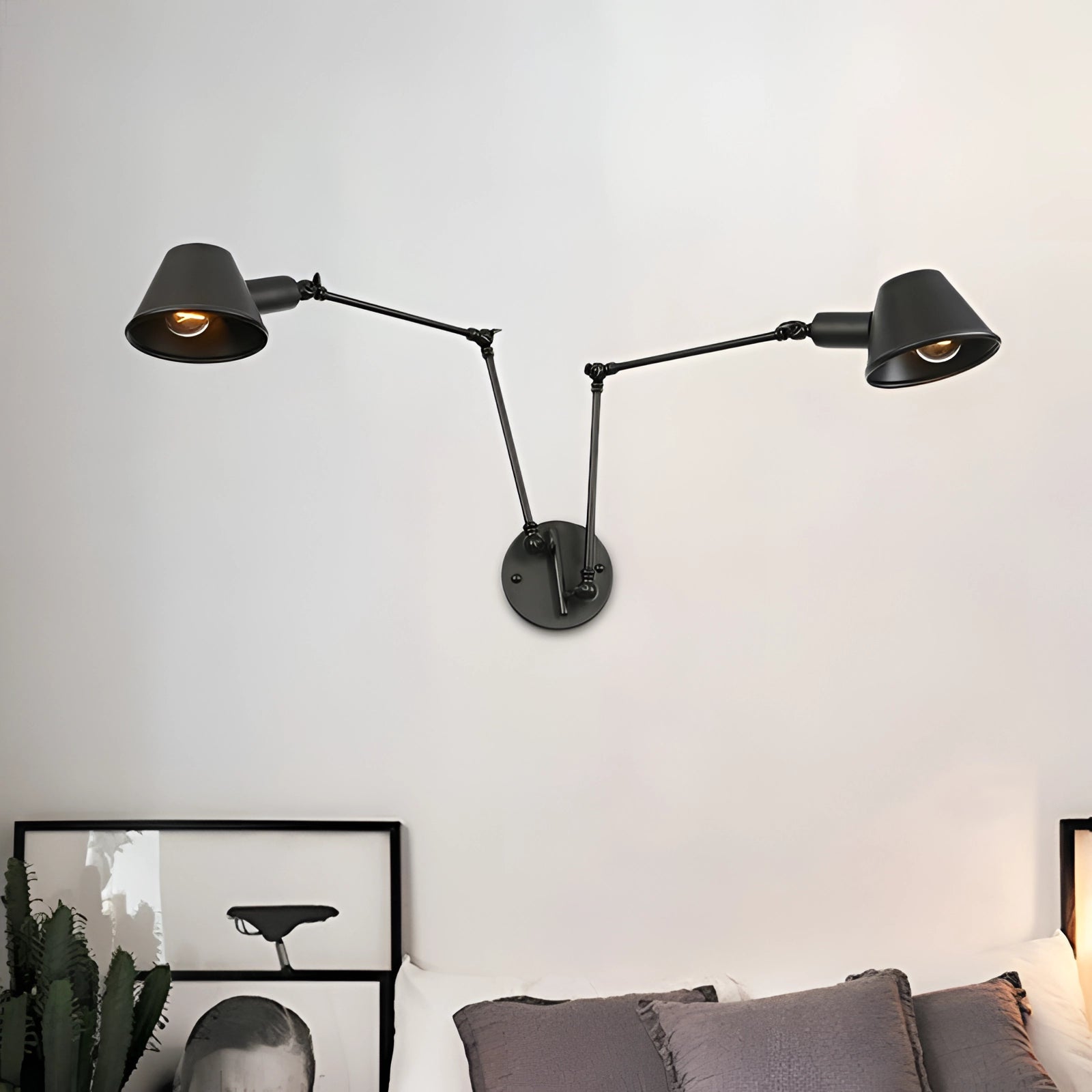 Adjustable triple-arm black wall sconce with two lights, featuring a modern industrial design, mounted on a white wall.