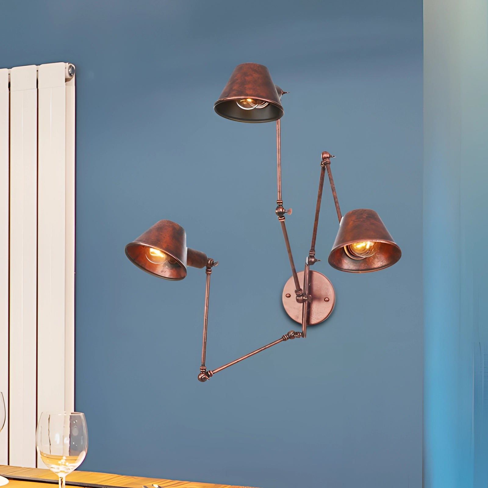 Adjustable triple-arm black wall sconce with a modern industrial design, featuring three rust-colored light fixtures, set against a wooden background.