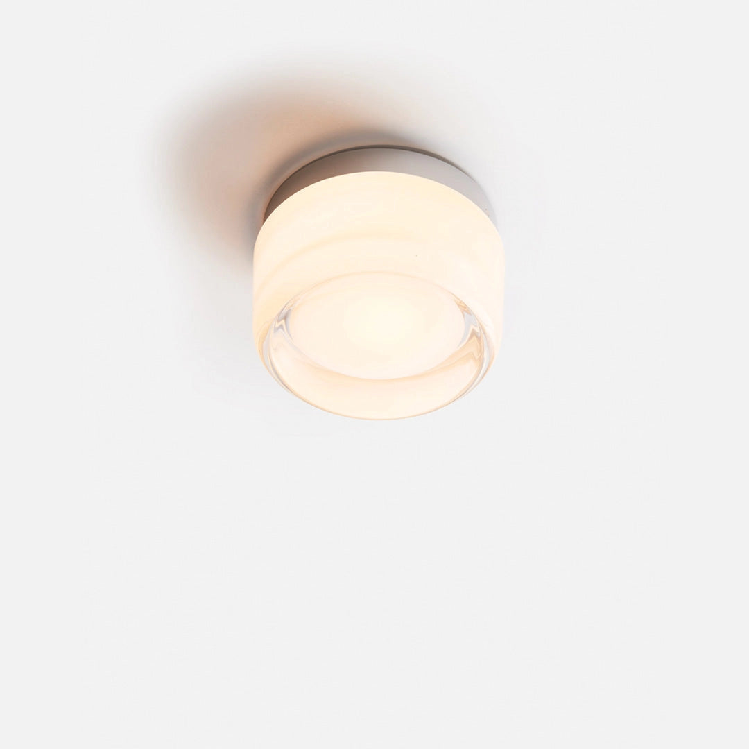 Modern minimalistic round amber glass ceiling light with a white finish, featuring a circular design with wood and metal accents, elegantly mounted as a ceiling fixture.