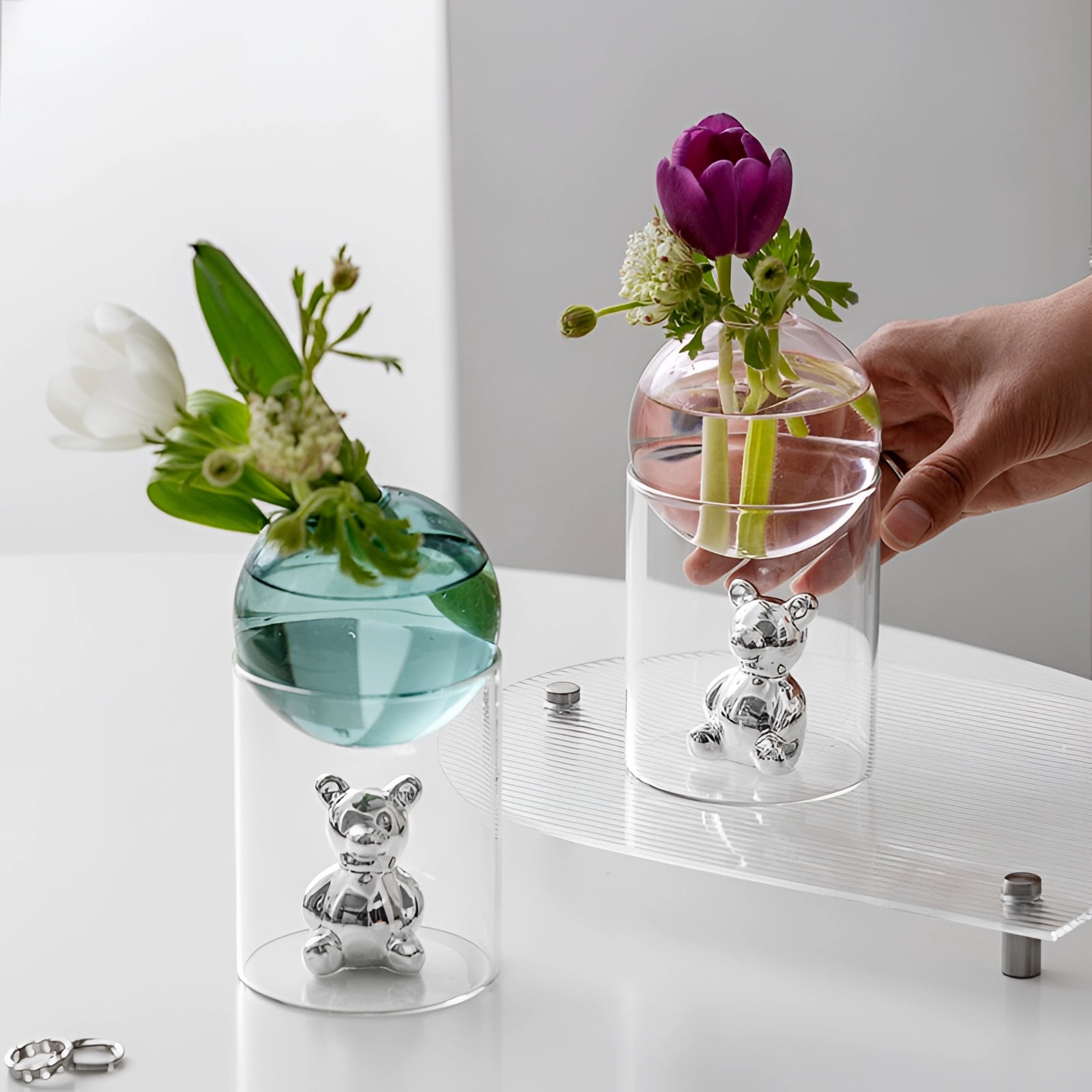 
Amber glass sphere with a gold bear design, used as a luxury decor piece, surrounded by a floral arrangement in a vase.