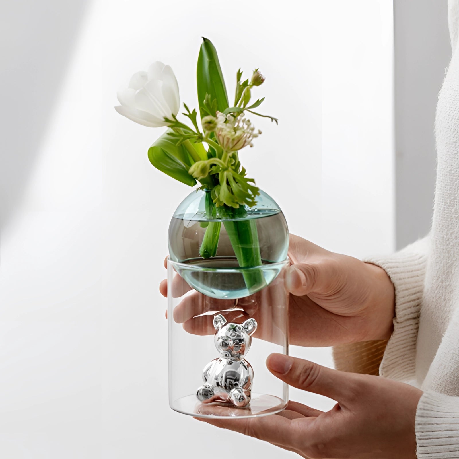 Amber glass sphere and gold bear luxury decor capsule featuring a sophisticated arrangement with a plant in a vase, showcasing a blend of modern elegance and artistic charm.