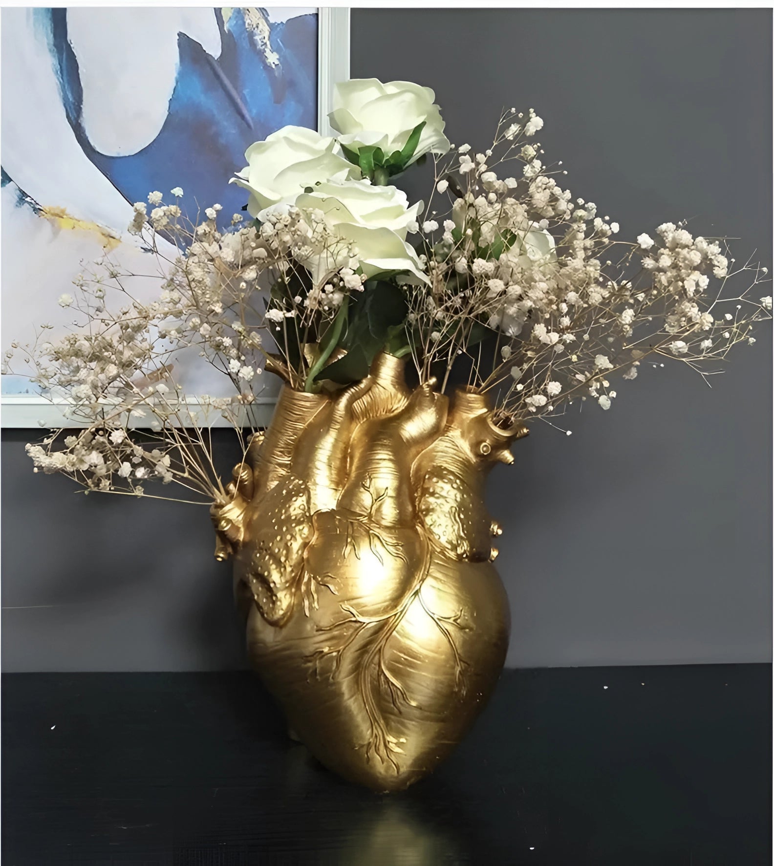 Anatomical heart-shaped vase filled with a vibrant arrangement of flowers and twigs, showcasing creative floral artistry.