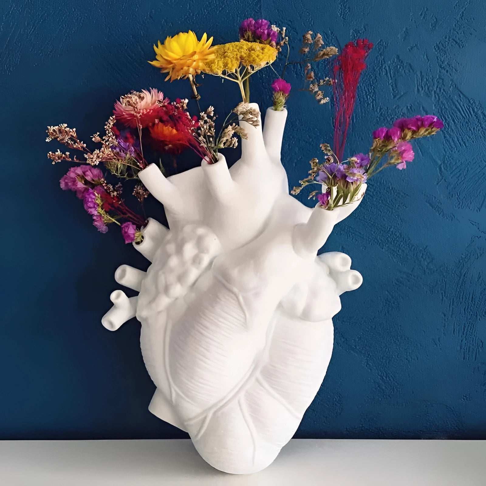 An artistic heart-shaped flower planter vase designed like an anatomical heart, filled with vibrant flowers, showcasing detailed petals and creative craftsmanship.