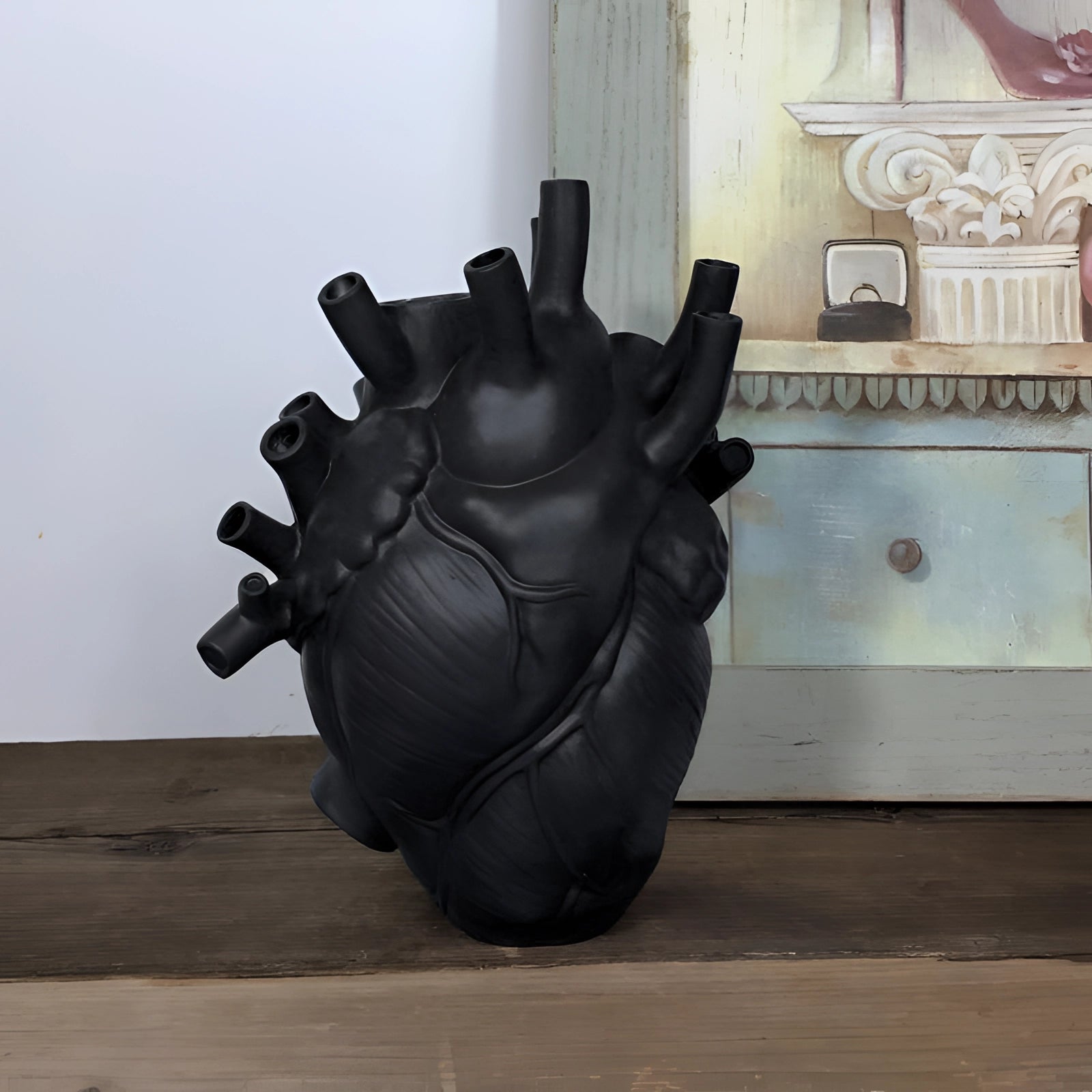 
A large, black anatomical heart vase made of ceramic, intricately designed as a romantic floral sculpture.