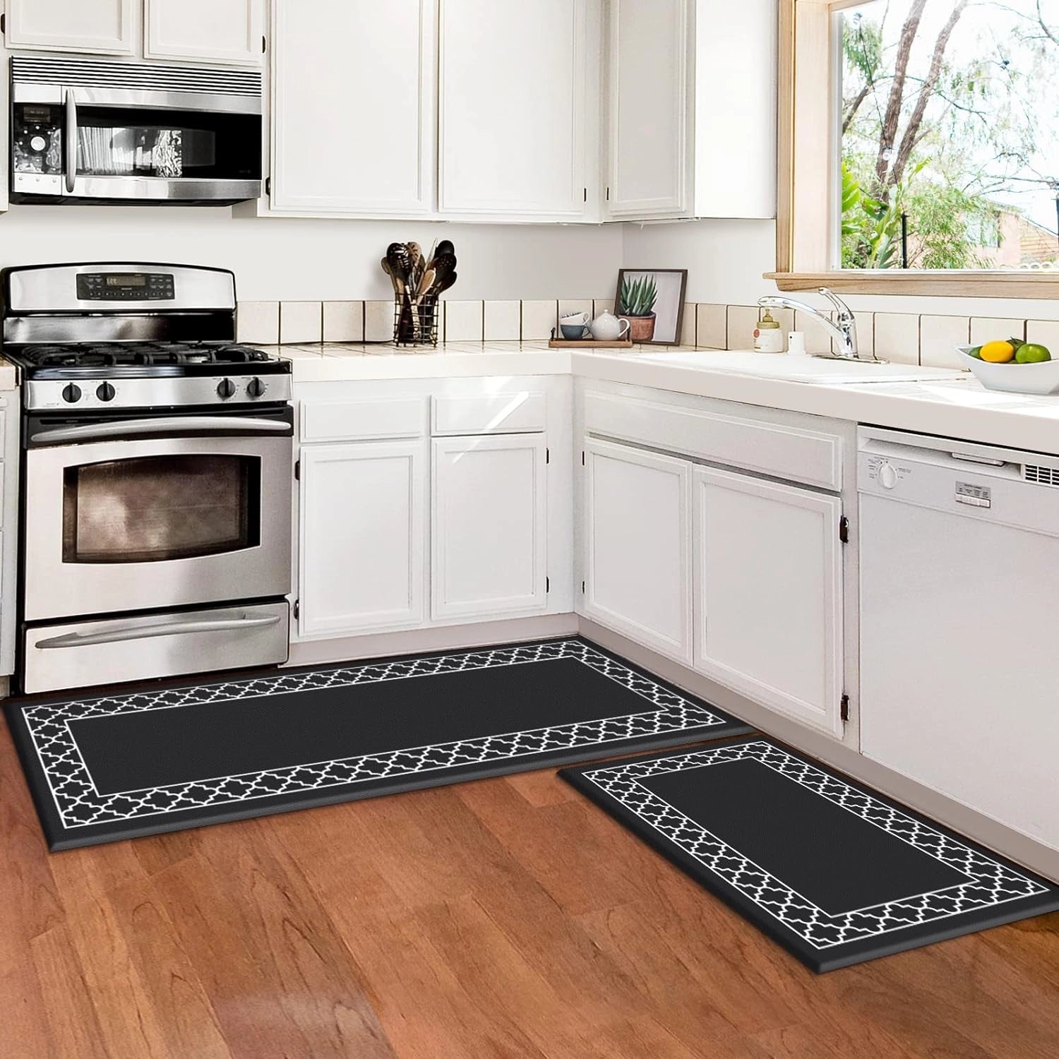 Anti-fatigue cushioned kitchen mat in black, shown in a 2-piece set with dimensions of 50x80cm and 50x120cm, placed on a kitchen floor in front of cabinetry and near a kitchen sink and stove, highlighting its ergonomic and slip-resistant features in a modern kitchen interior.