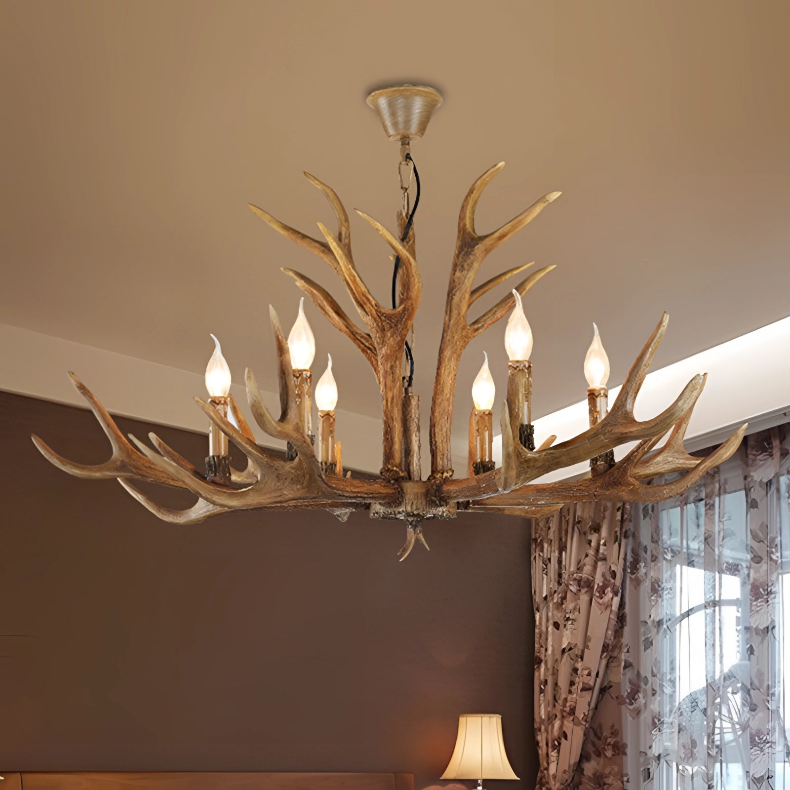 Antler chandelier with rustic lodge cabin decor, featuring branches and twigs, providing a natural and artistic lighting fixture in an interior design setting.