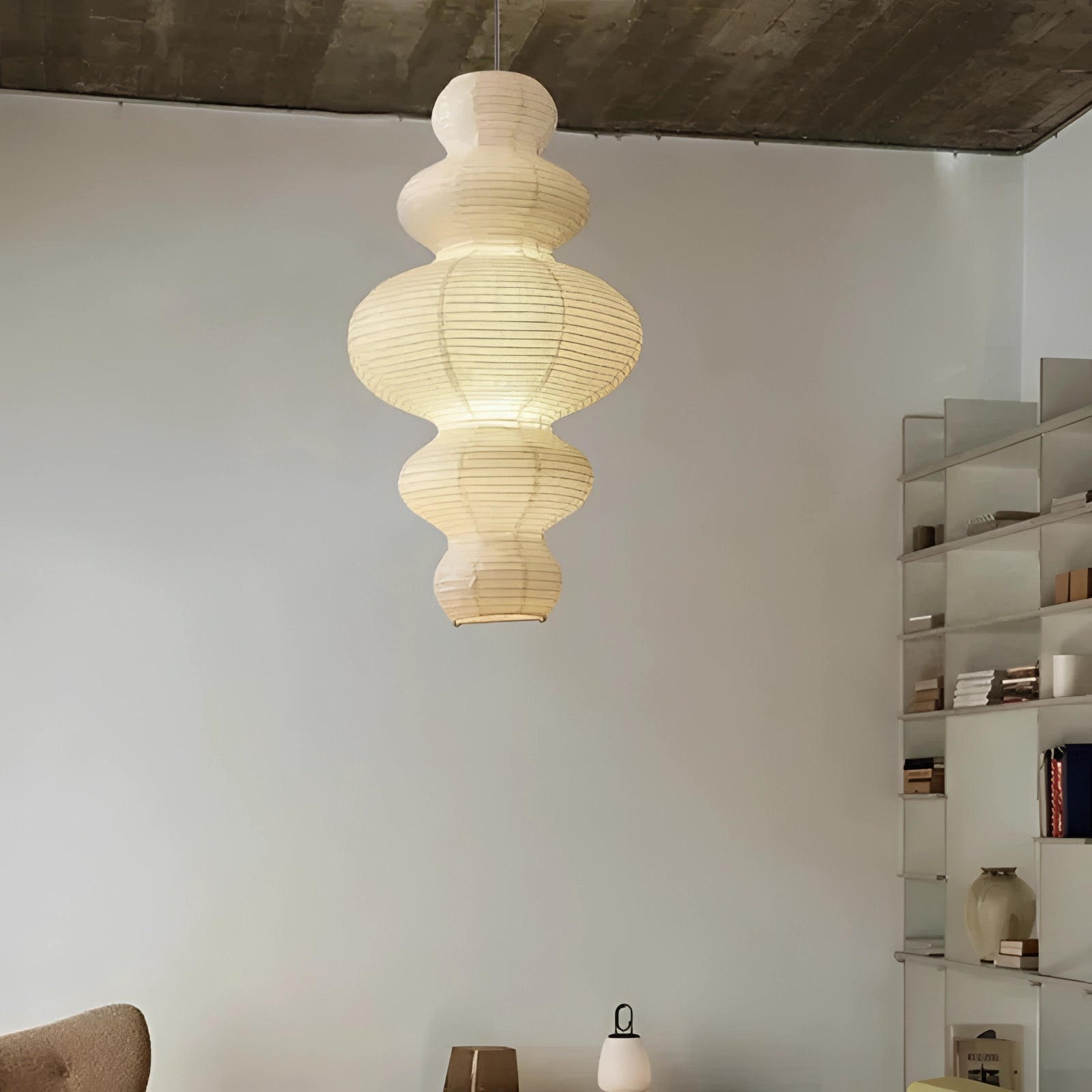 Asian-inspired pendant light with a round rice paper and natural fiber shade, featuring a white finish and wooden accents, elegantly suspended from the ceiling in a modern interior setting.