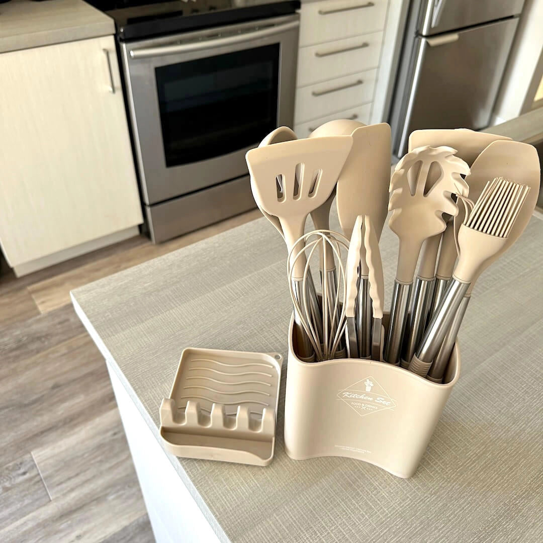 Beige silicone kitchen utensil set arranged neatly on a wooden table, showcasing various cooking tools designed for heat resistance and non-stick use, complementing modern kitchen interior design.