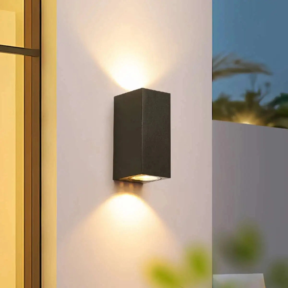 Modern black cylindrical LED outdoor wall lamp mounted on a wooden wall, weather-resistant sconce illuminating the area.