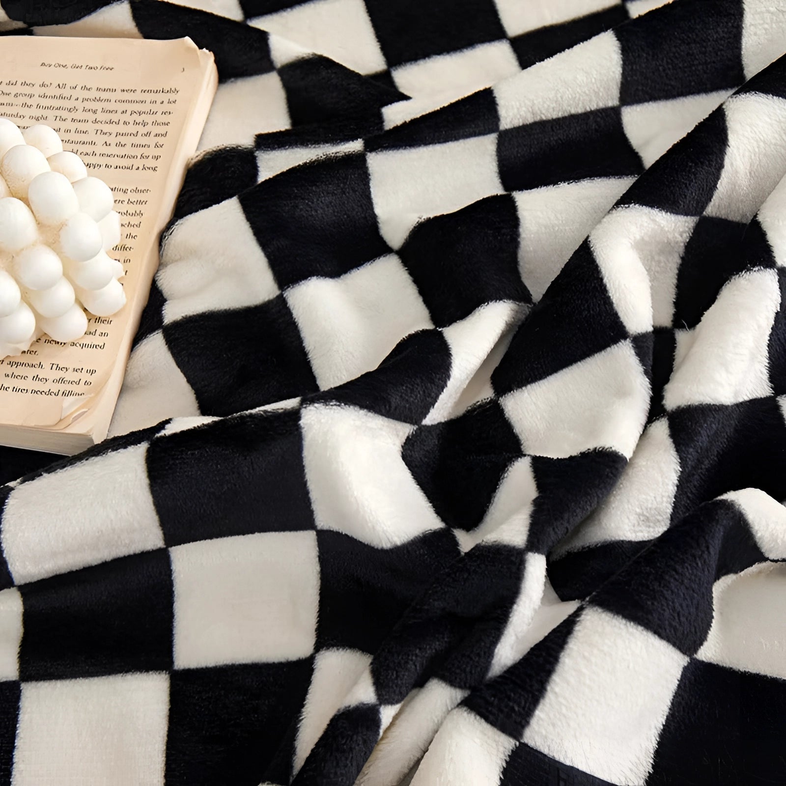 Black and white checkered blanket featuring a modern geometric pattern, showcasing a classic black-and-white color scheme in a rectangular textile design.