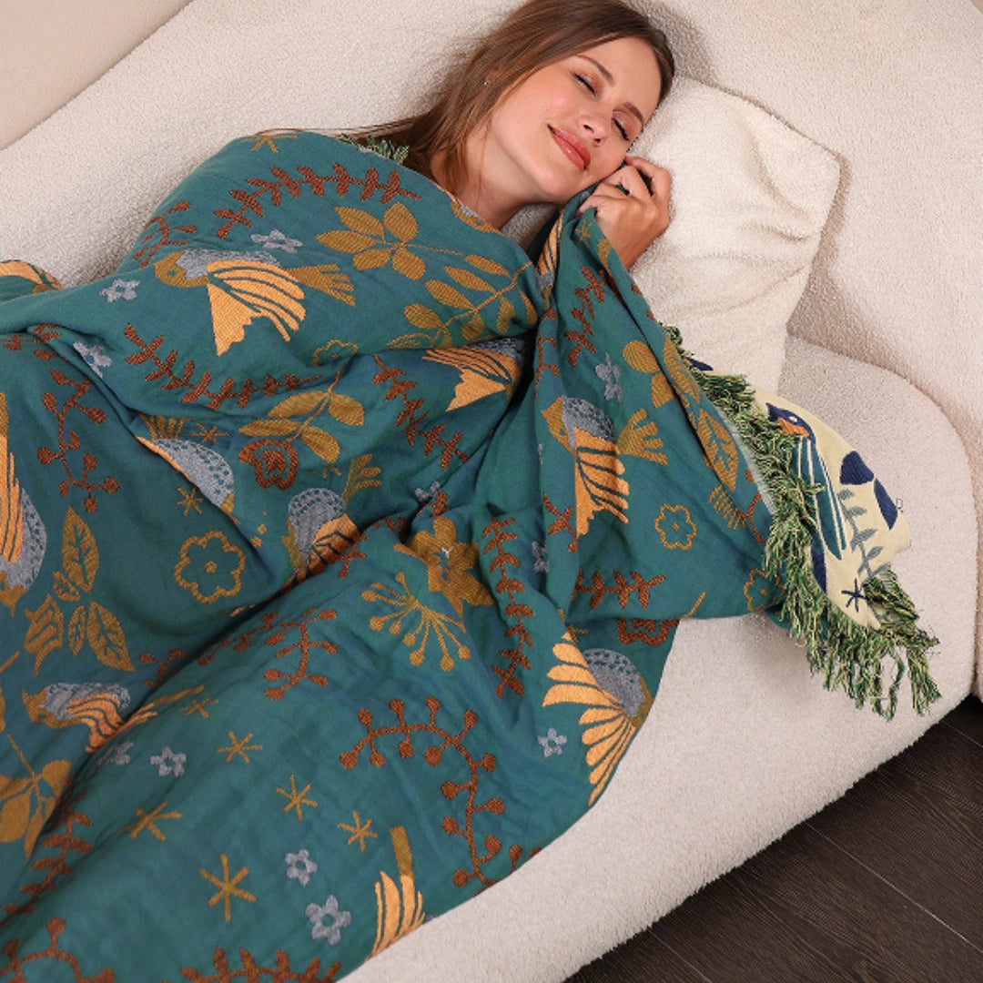 Bohemian Bird Pattern Throw Blanket in Blue and Beige with Fringe Decor, draped over a person smiling, focusing on the textile design and comfort of the blanket.