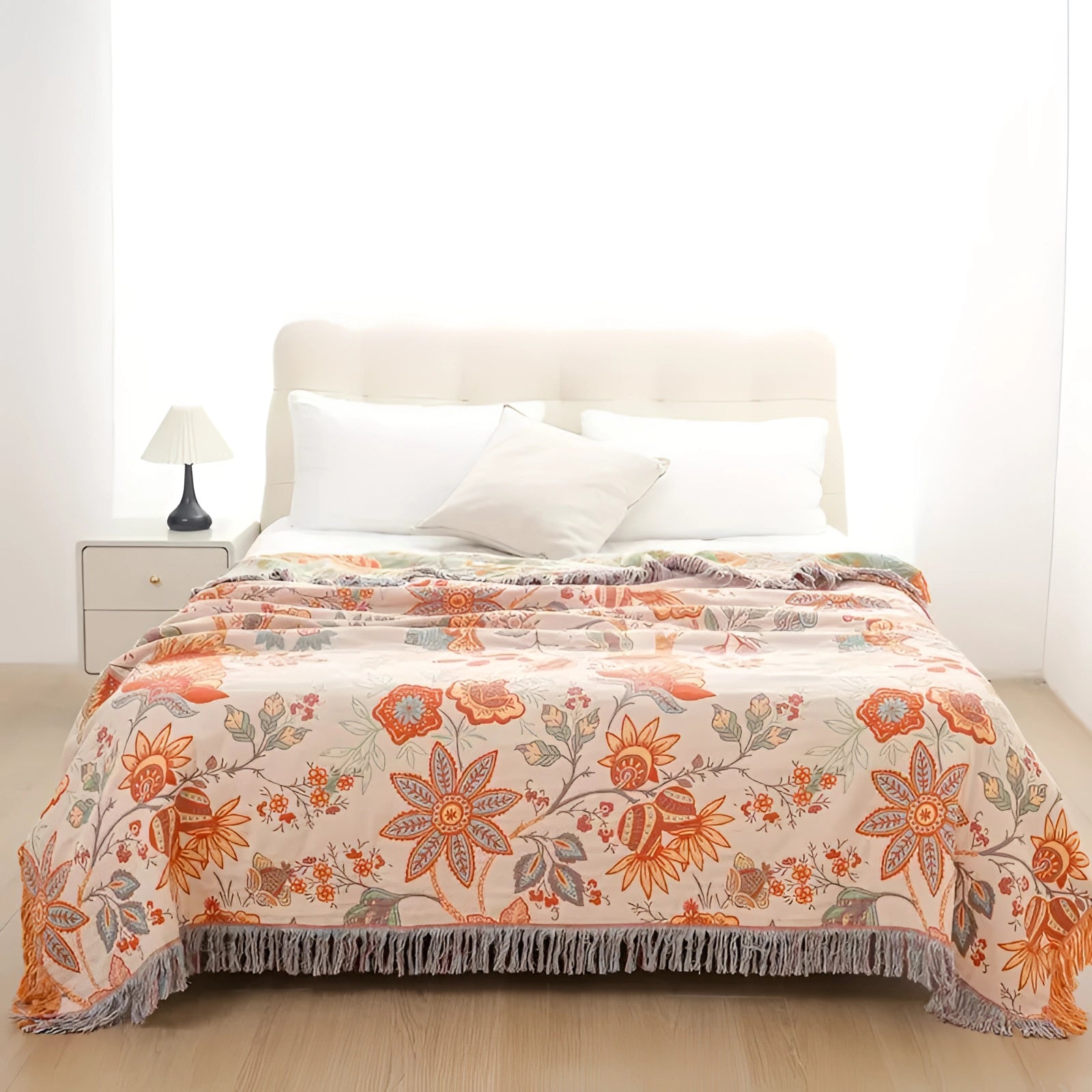 Bohemian floral fringed throw blanket in soft, cozy cotton draped over a wooden chair, showcasing its orange hue and intricate textile pattern, with hardwood flooring visible in the background.