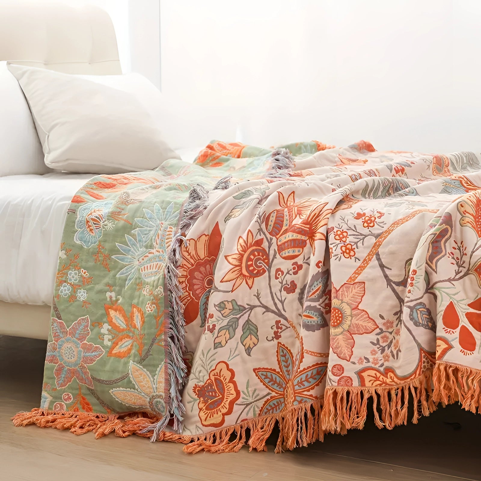 Bohemian floral fringed throw blanket in a soft and cozy cotton material, featuring an orange color with an intricate pattern, draped over a floor in a stylish interior setting.