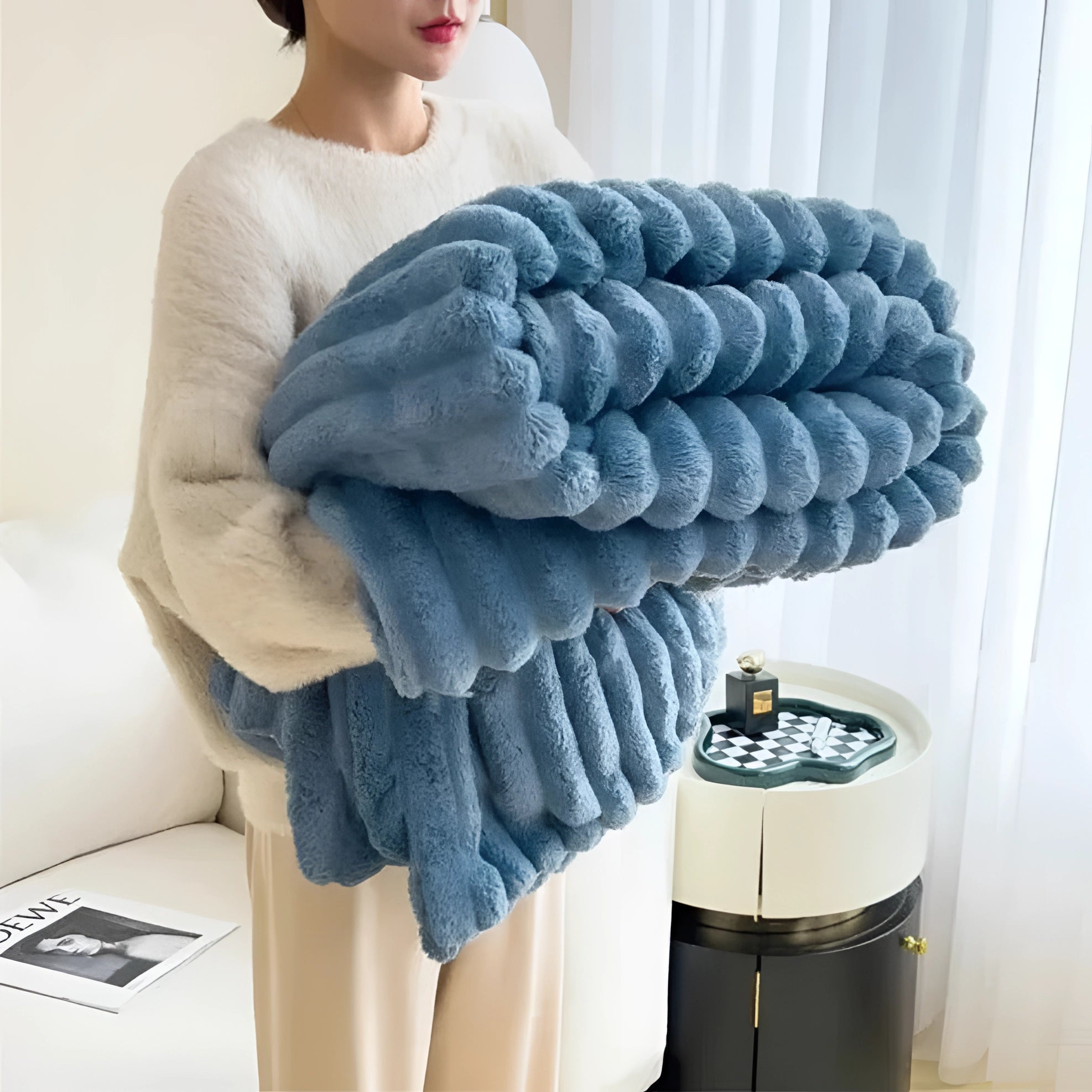 Chunky knit blanket in ocean blue, draped over a sofa, showcasing its thick woolen texture and cozy appearance.