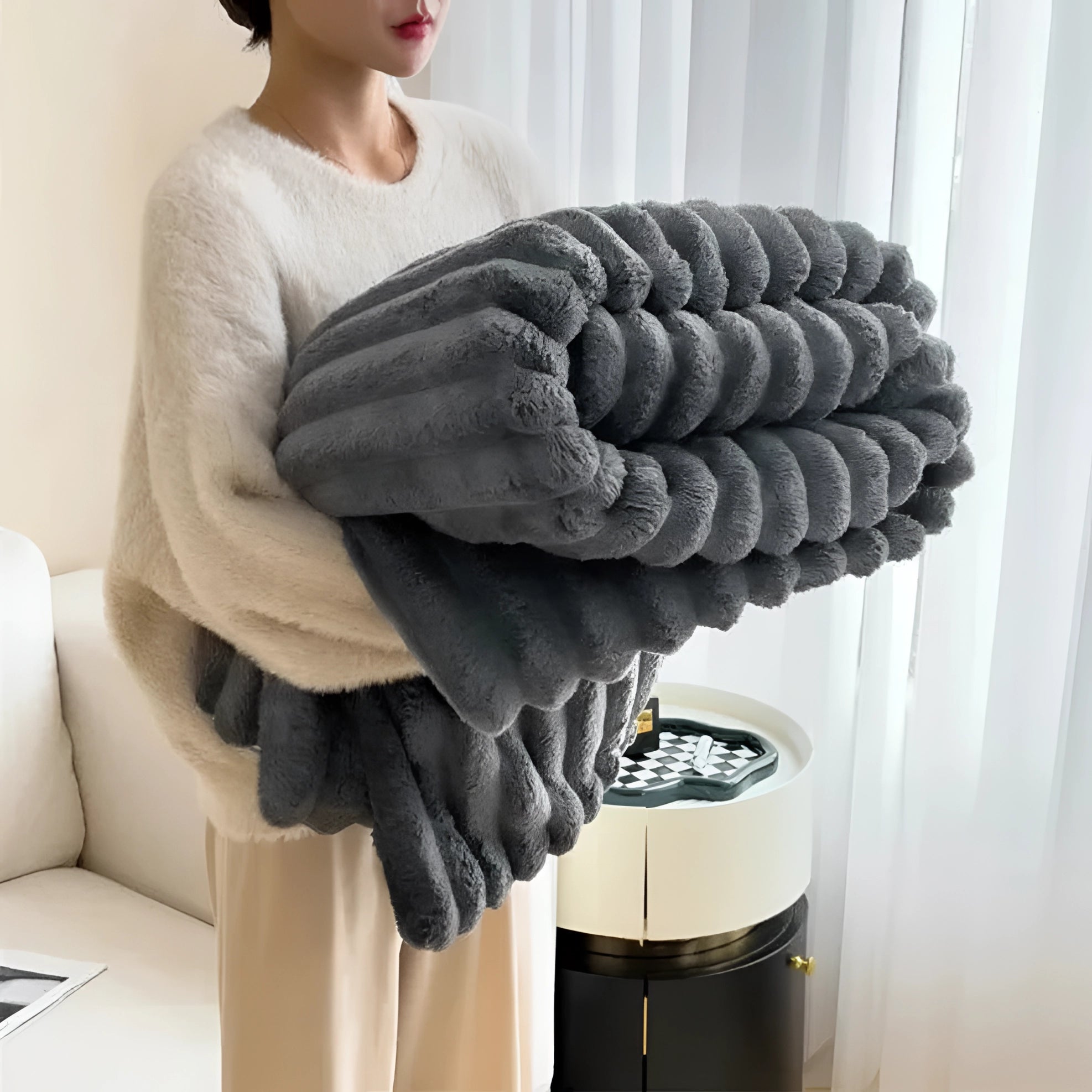 
A chunky knit blanket in a charcoal gray color, handmade and draped over a sofa, offering a cozy and stylish addition to the living space.