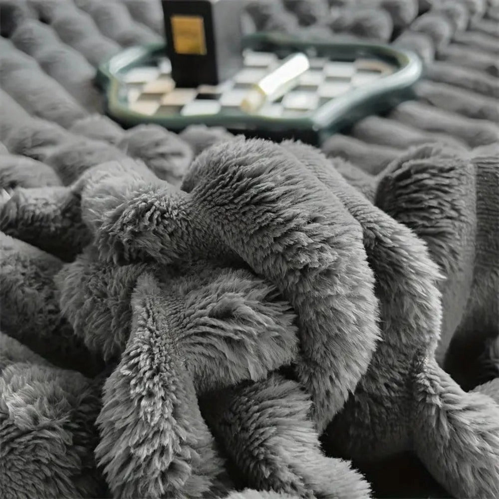 Chunky gray knit blanket with a textured pattern, displayed on a sofa.