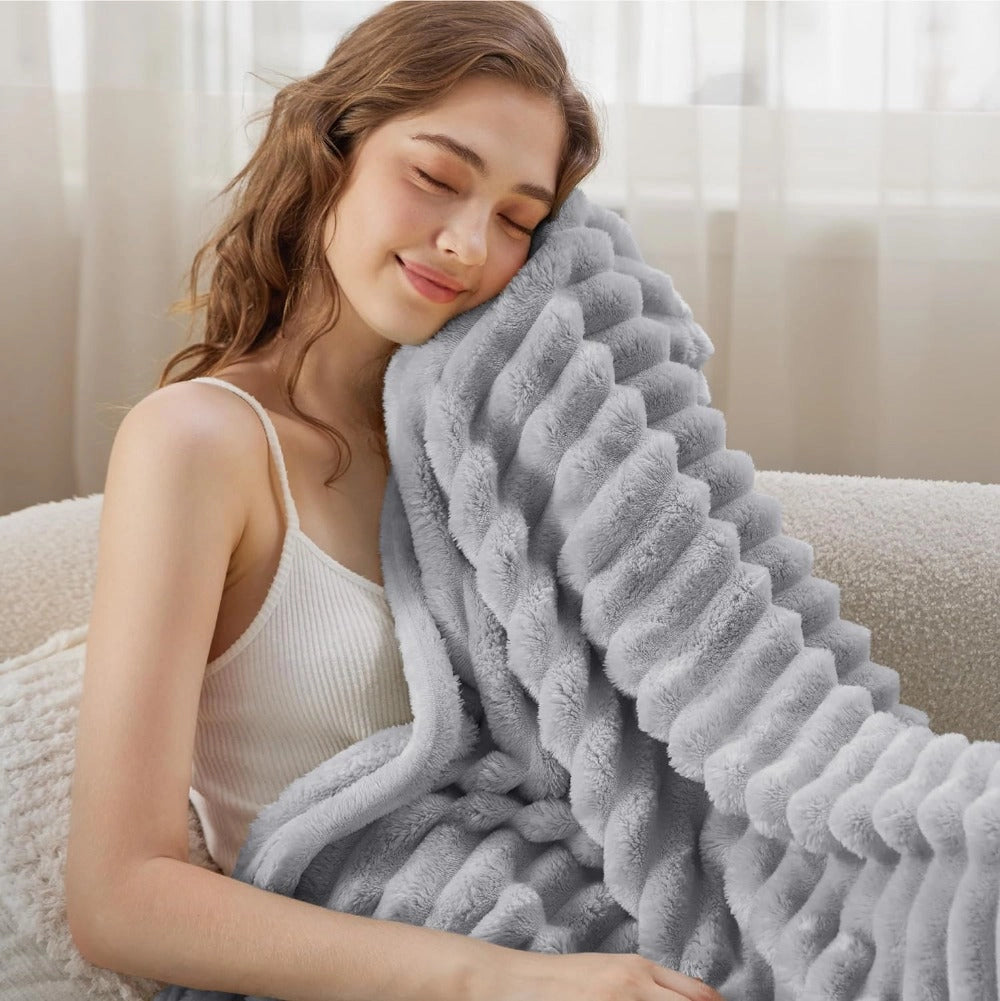 Gray chunky knit blanket draped over a cozy sofa, showcasing its thick, handmade texture and inviting warmth.