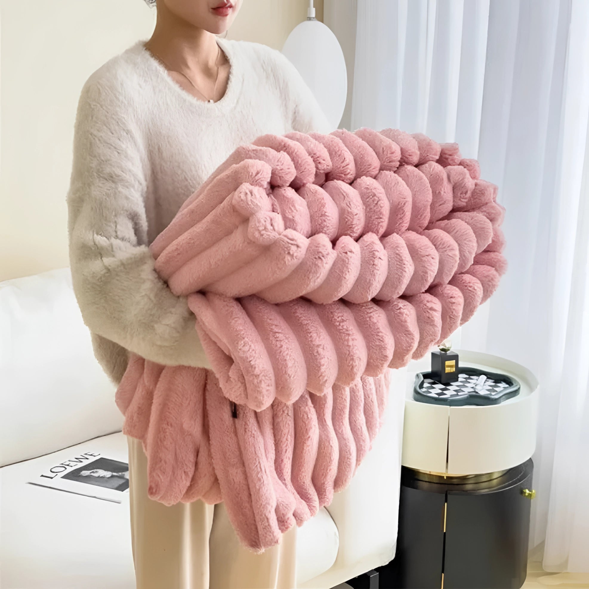 Chunky knit blanket in rose blush color draped over a sofa, showcasing its thick wool texture and cozy design.