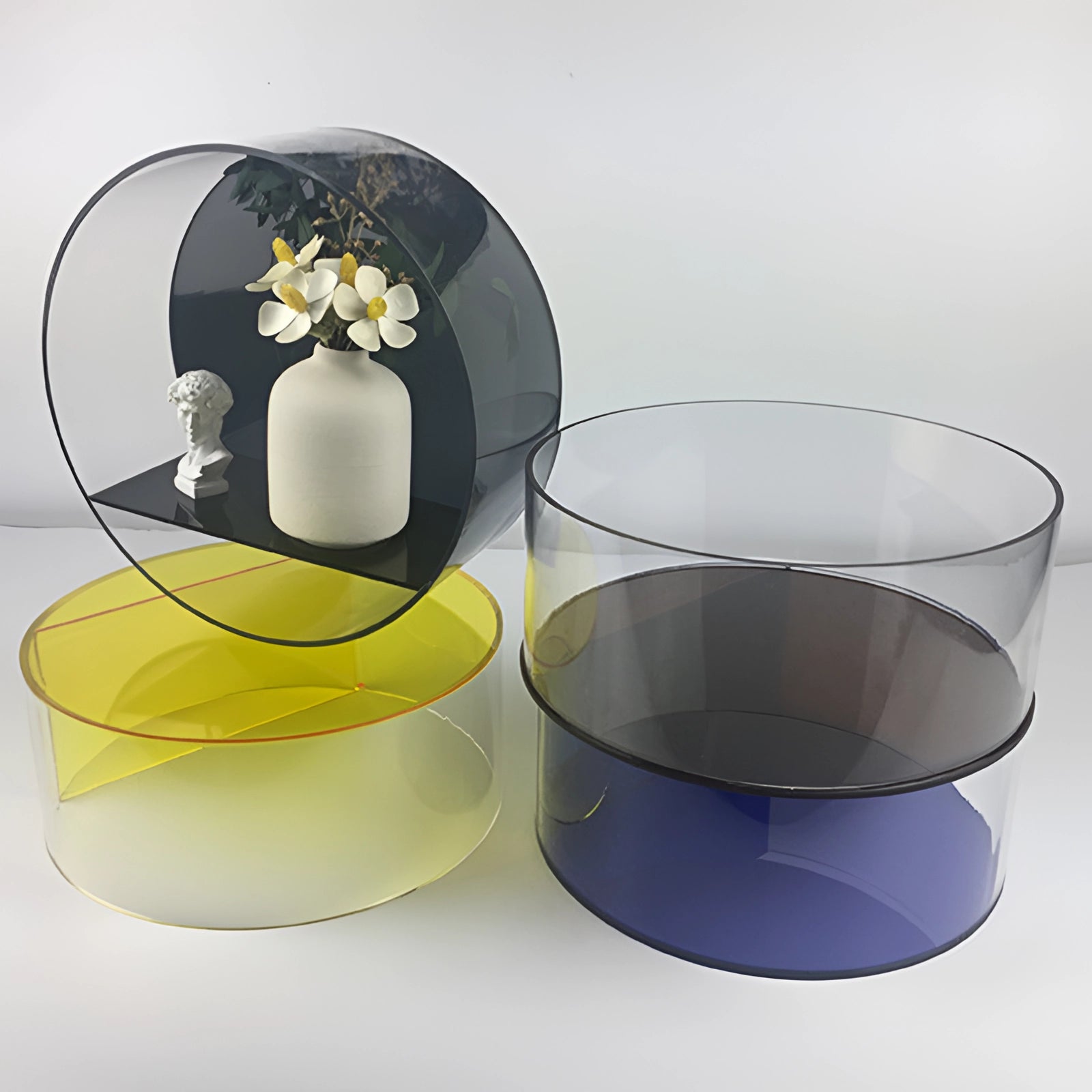 Circular black glass floating shelf mounted on a wall, adorned with modern minimalist decor including drinkware and dishware such as cups and bowls.