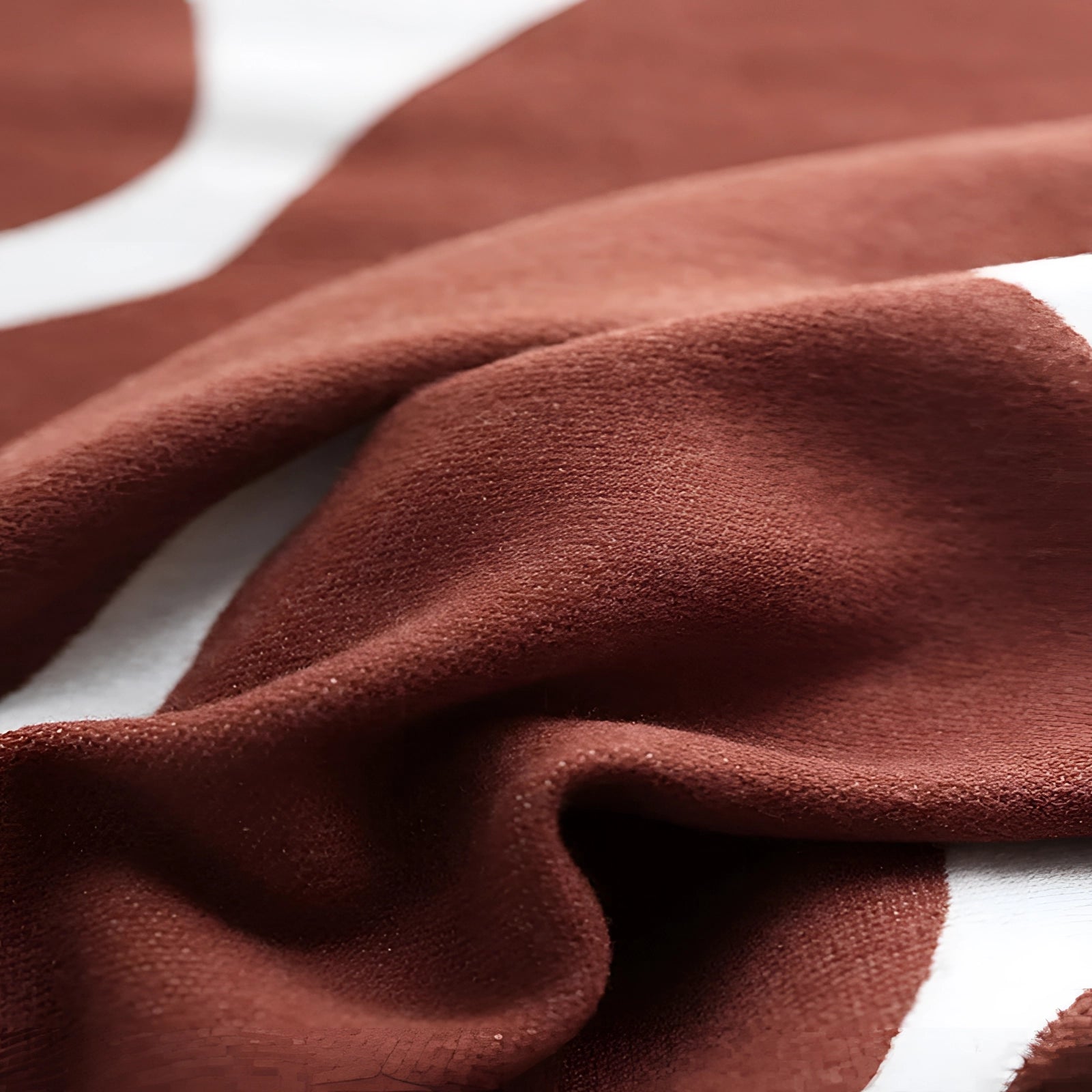 Brown and white cow print throw blanket with an animal pattern in soft fleece material, draped over a surface showing its distinct pattern and texture.