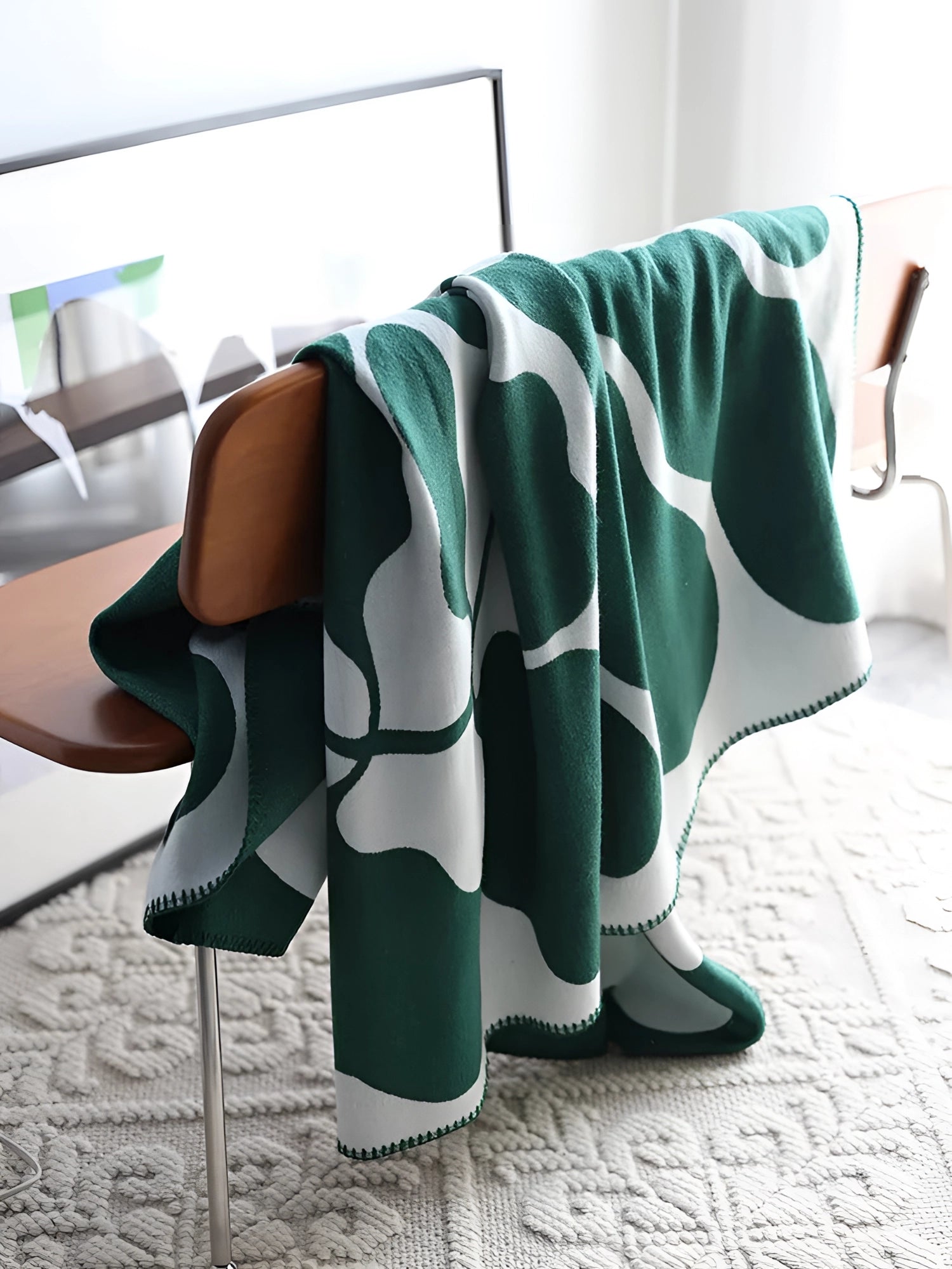 Brown and white cow print throw blanket with a soft fleece texture draped over a surface, showcasing its unique animal pattern.