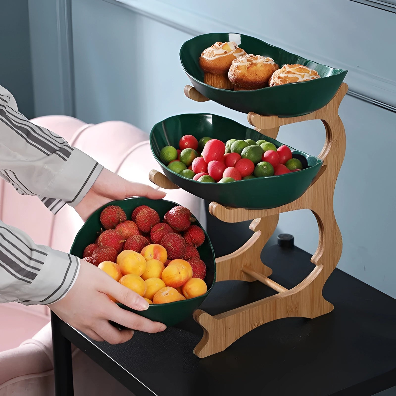 Double-decker ceramic snack bowl with bamboo stand, containing a variety of fruits such as oranges, elegantly arranged for serving or display, showcasing a modern and organized presentation.