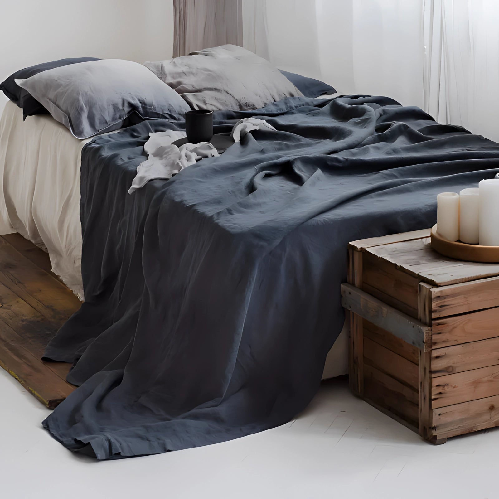 Eco-friendly linen duvet cover in dark blue, displayed on a bed with a wooden bed frame, set against a neutral-toned room with light flooring.