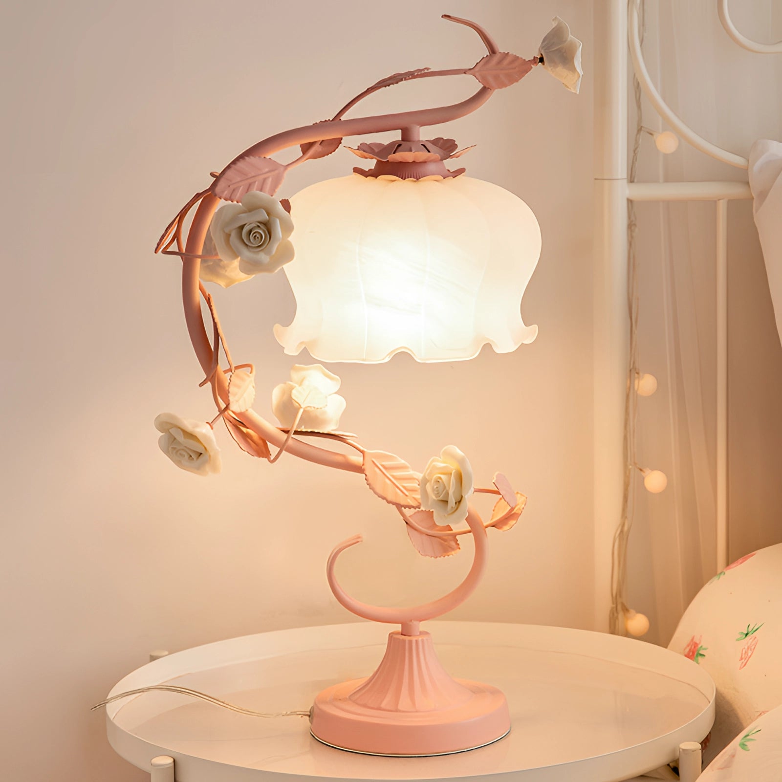 Elegant pink rose table lamp with shabby chic floral vine design on wooden base, displayed on a table in a stylish interior setting.