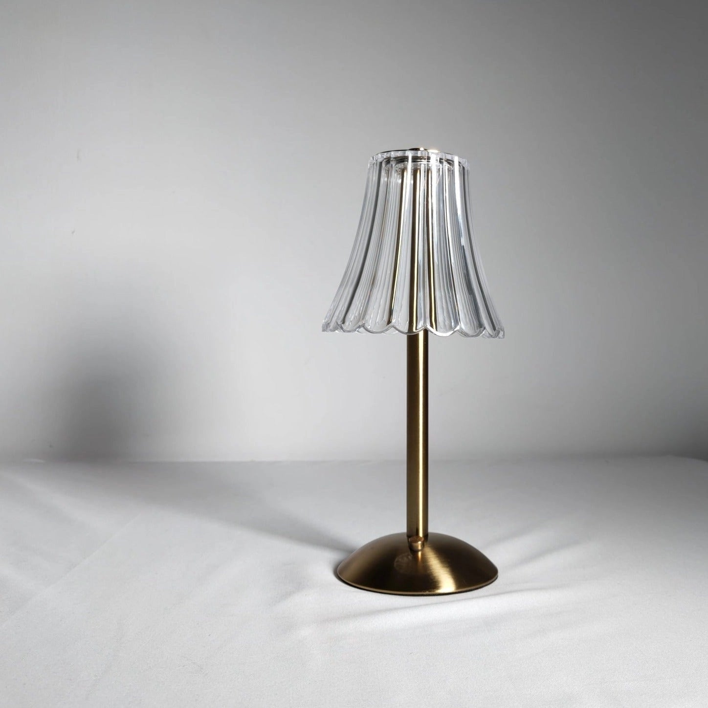 Elegant pleated table lamp with acrylic lampshade, modern gold base, and LED bulb, featuring artistic design elements and natural material accents.