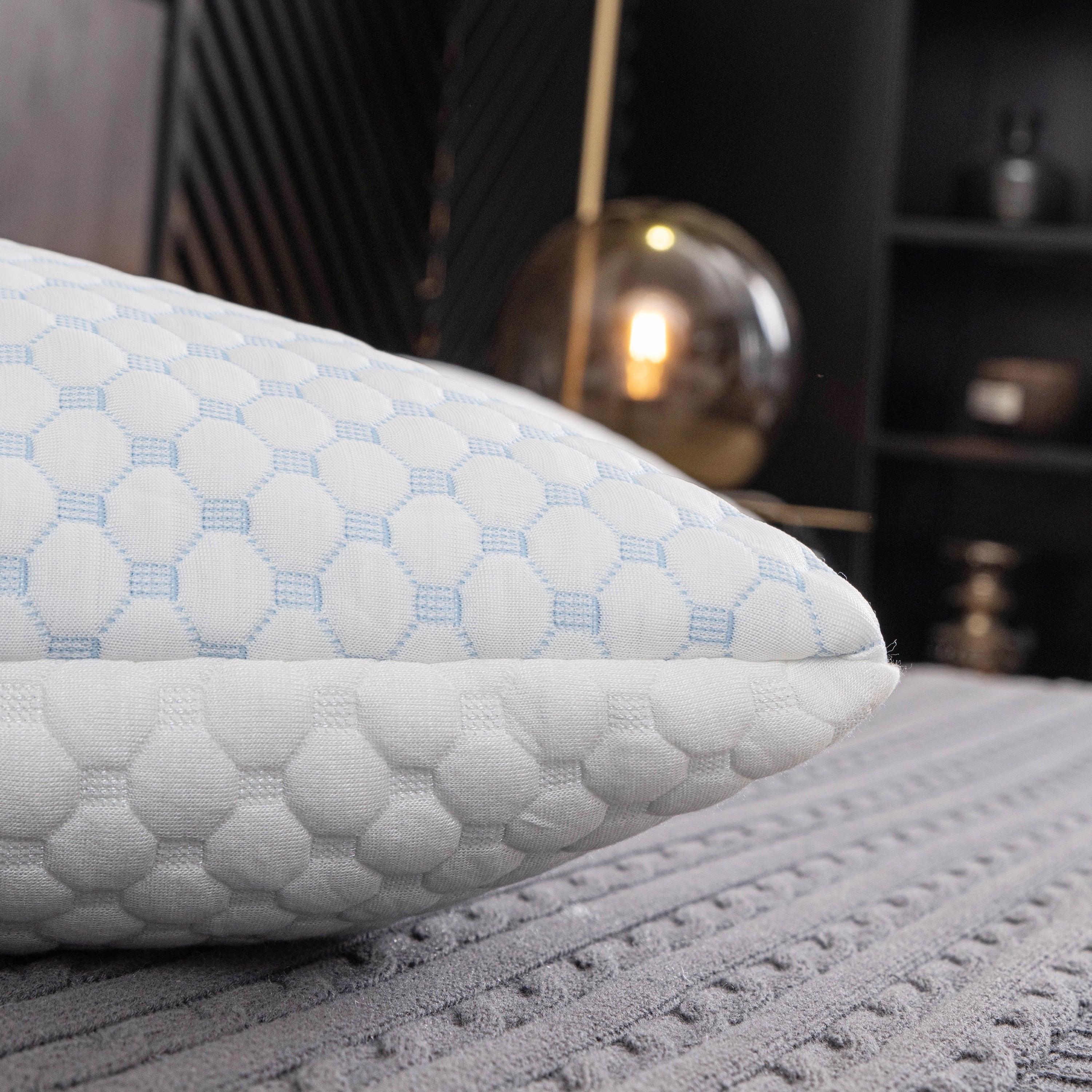 Ergonomic cooling memory foam pillow with hypoallergenic luxury design, featuring a rectangular shape and soft textile pattern, positioned on a couch.