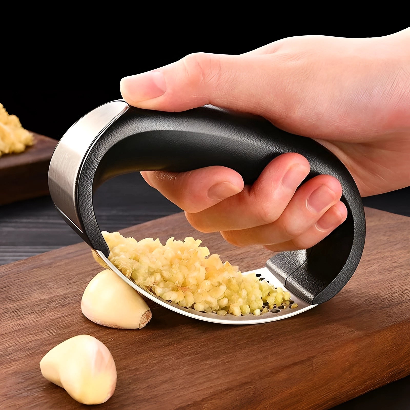 Ergonomic stainless steel garlic press designed for easy squeezing, shown in use with a hand pressing garlic cloves, highlighting its rust-proof and efficient garlic crushing capability in a kitchen setting.