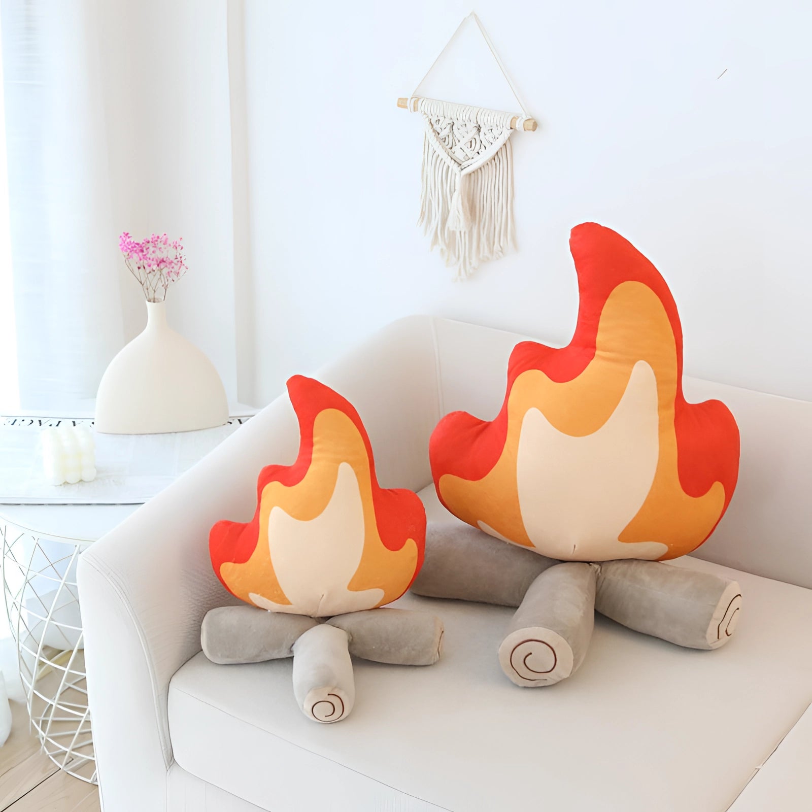 Flame-shaped plush pillow in vibrant orange displayed in a modern living room setting with artistic home decor, featuring elements like wood accents and a stylish lamp.