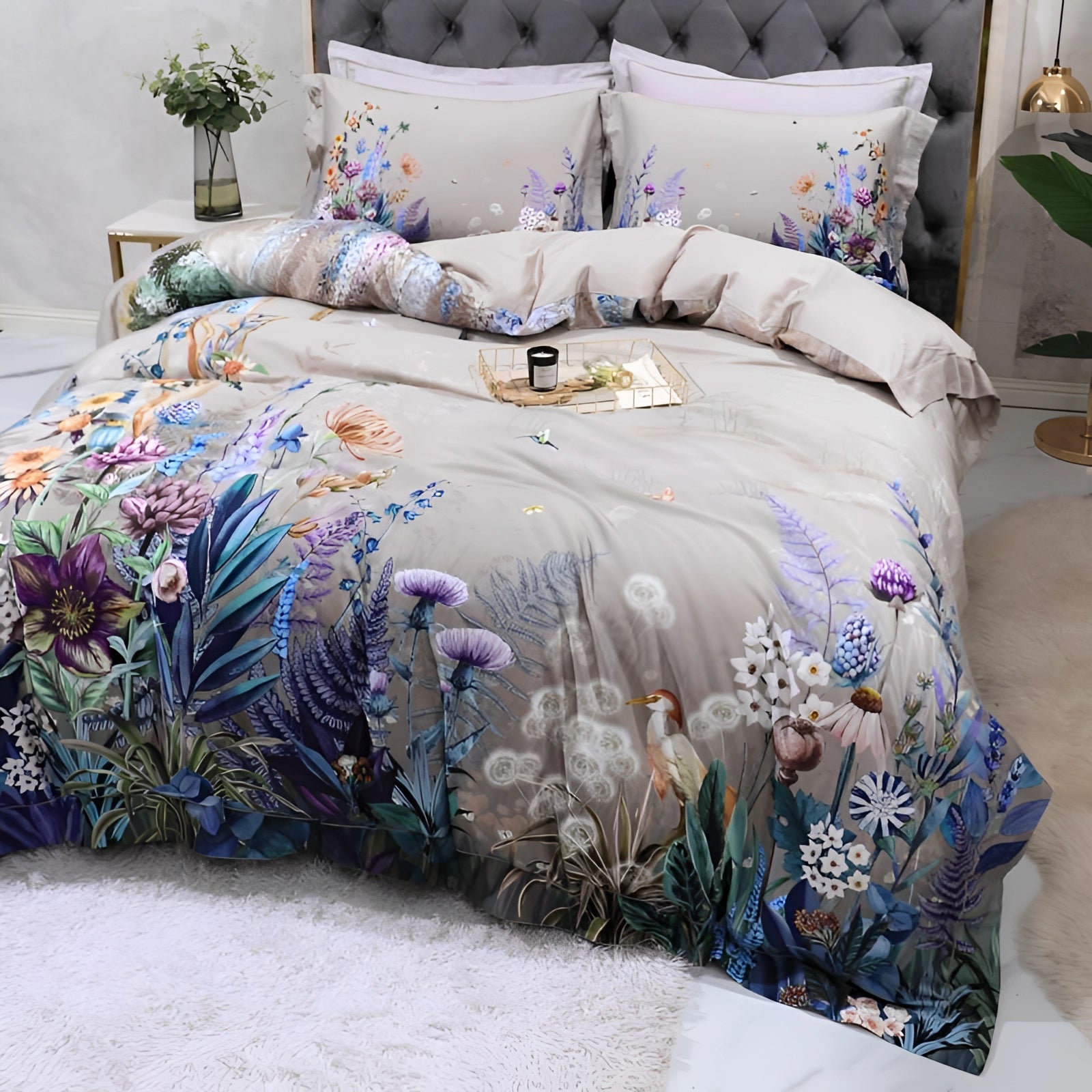 Elegant floral bedding set featuring a designer duvet and comforter in a predominantly white and azure color scheme, styled in a beautifully designed interior. The bed is adorned with plush pillows, surrounded by elements of creative arts and a touch of greenery from a nearby plant, creating a sophisticated and serene bedroom decor.