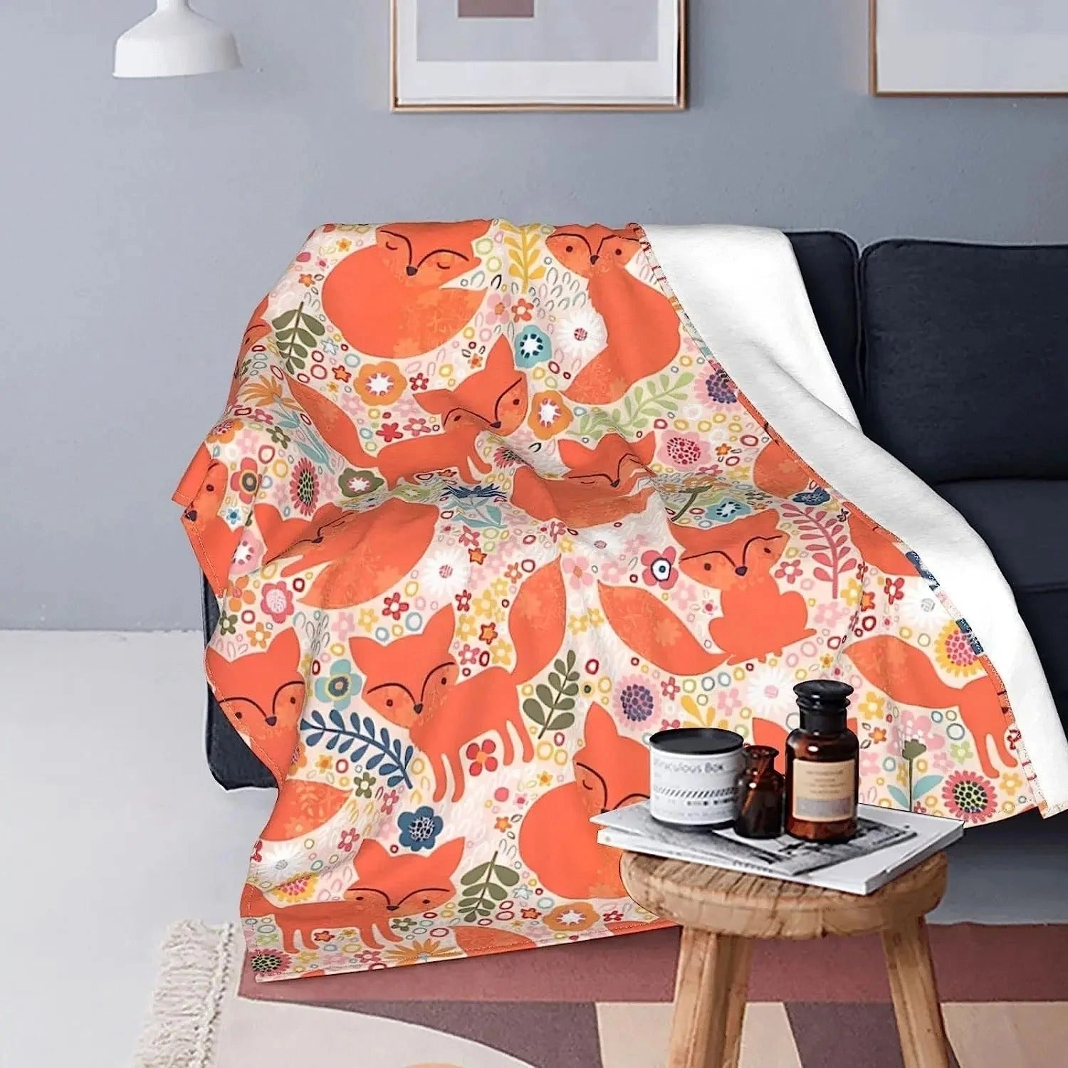 A cozy orange fox print throw blanket draped over a wooden chair, adding comfort and a whimsical touch to the interior decor of a room with warm lighting.