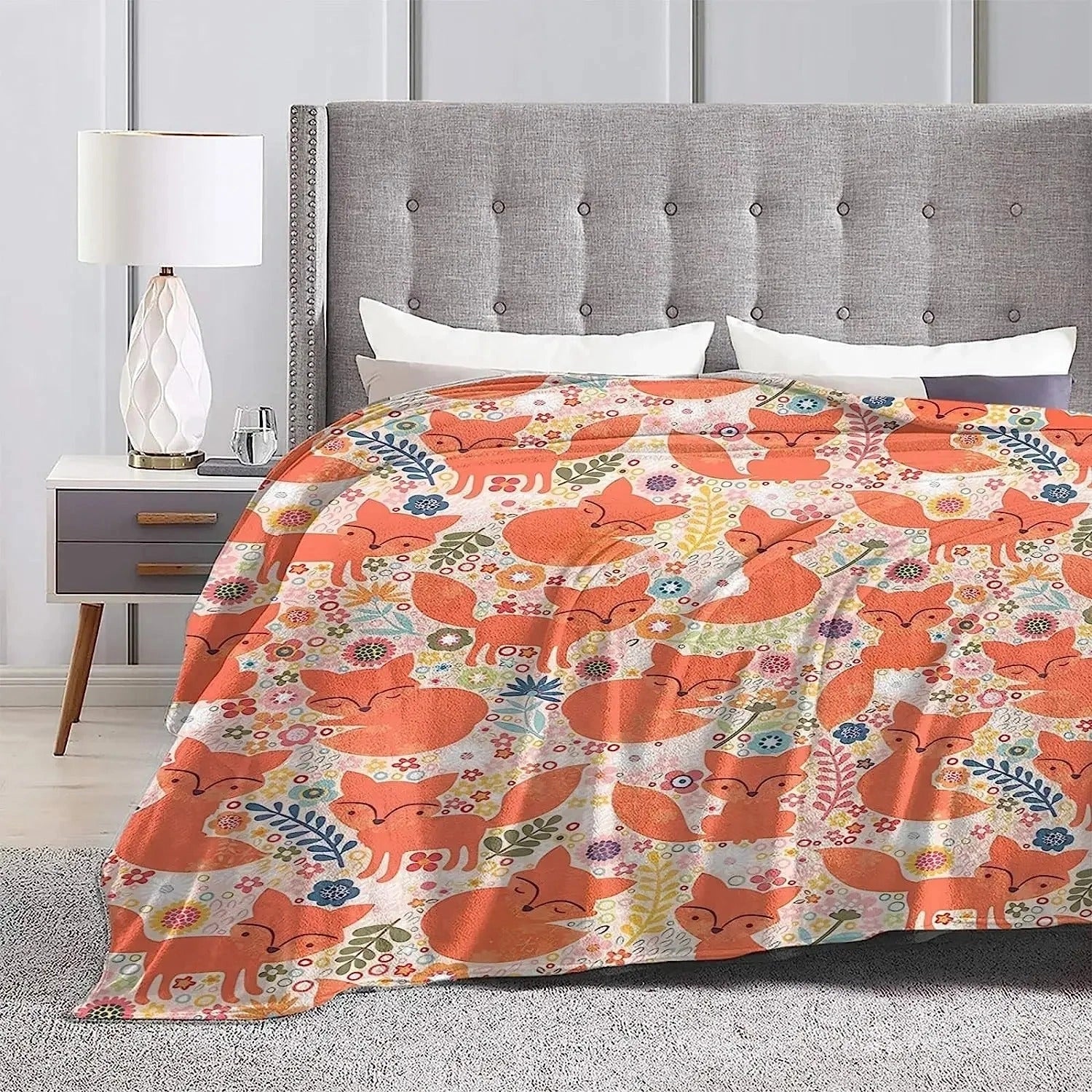 Fox Print Throw Blanket featuring a cute woodland design in shades of orange, draped over a wooden chest of drawers, adding a touch of comfort and charm to the interior decor.