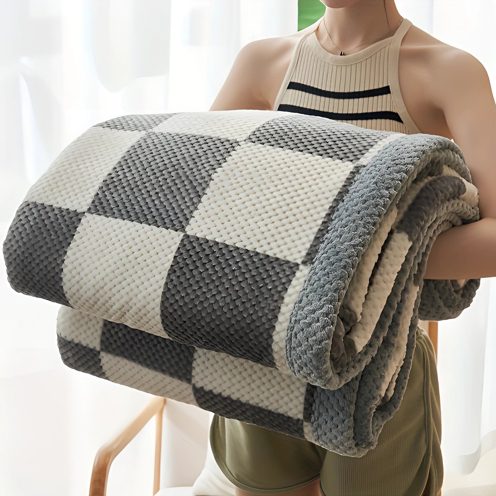 Black and white oversized quilt blanket with geometric patterns, draped over a couch, highlighting comfort and hypoallergenic features.