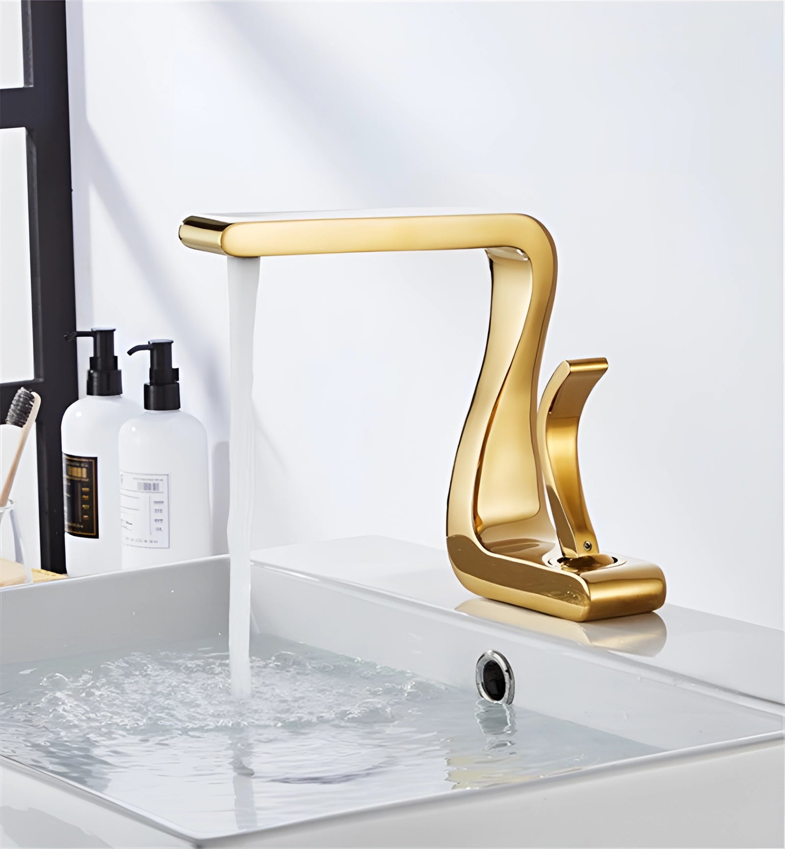 
A modern gold bathroom faucet with a square design, elegantly positioned over a sink. The faucet features sleek, angular lines and a luxurious finish, complementing the contemporary bathroom decor.