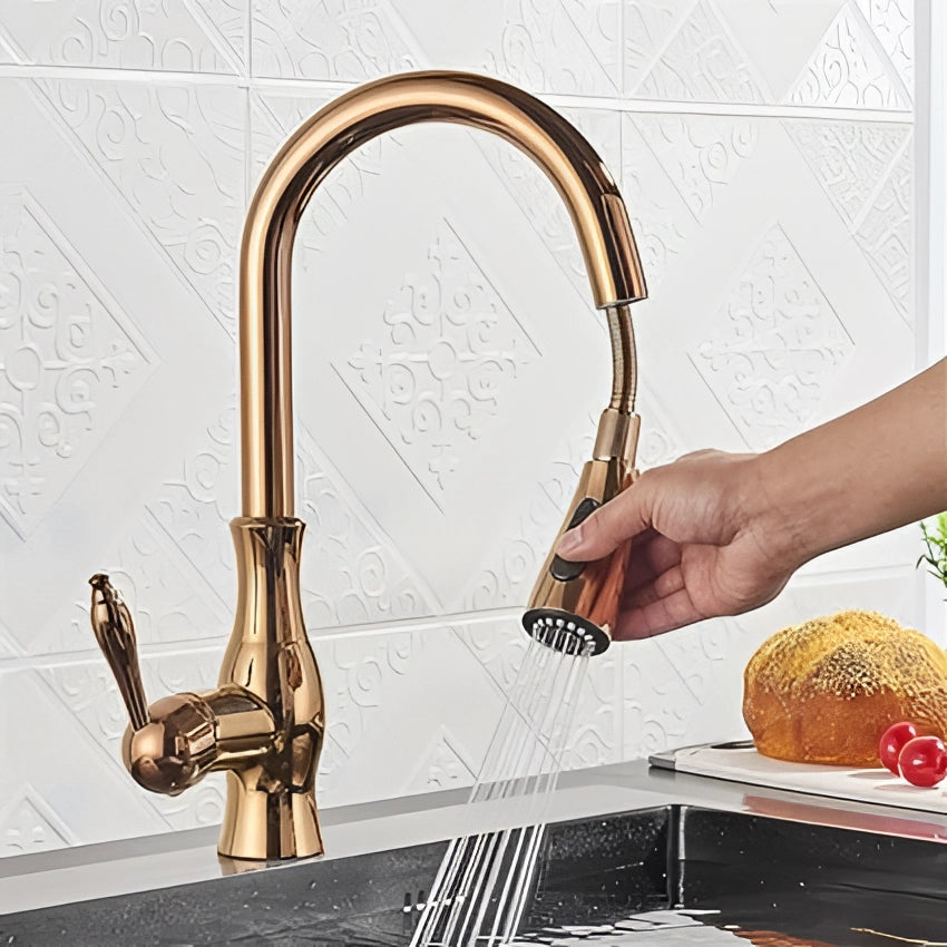 Gold brass kitchen faucet with a pull-down spray and high-arc spout, featuring a modern design, installed over a kitchen sink.