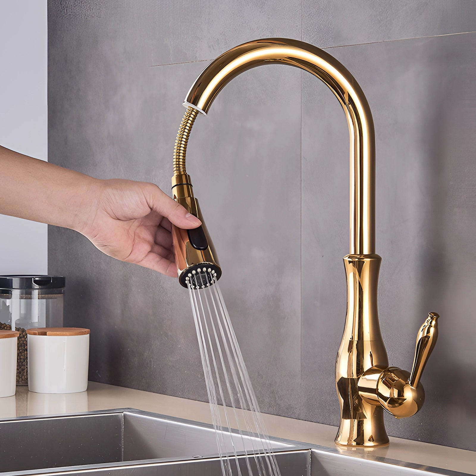 Gold brass kitchen faucet with a pull-down spray feature, high-arc design, and modern aesthetic, installed on a countertop sink.