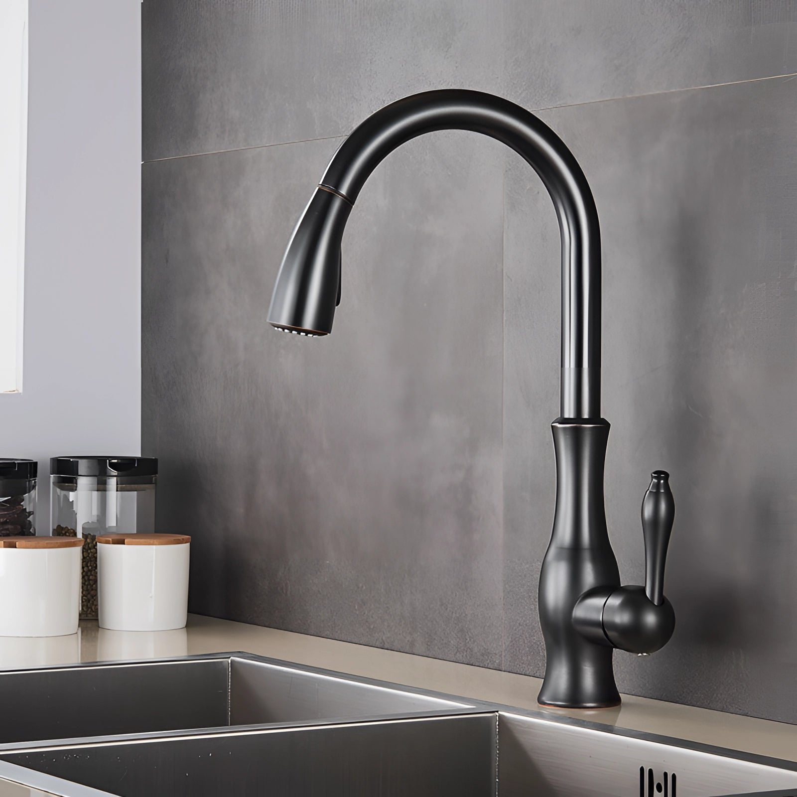 Gold brass kitchen faucet with a pull-down spray and high-arc design, installed on a grey countertop next to a sink, showcasing a modern and sleek aesthetic in the kitchen interior.