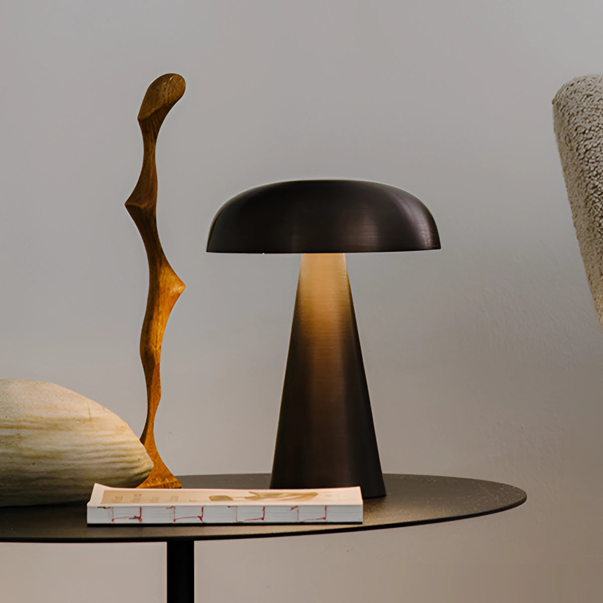 A sleek modern gold mushroom table lamp with a brushed metallic finish, placed on a wooden surface in a stylishly designed interior.