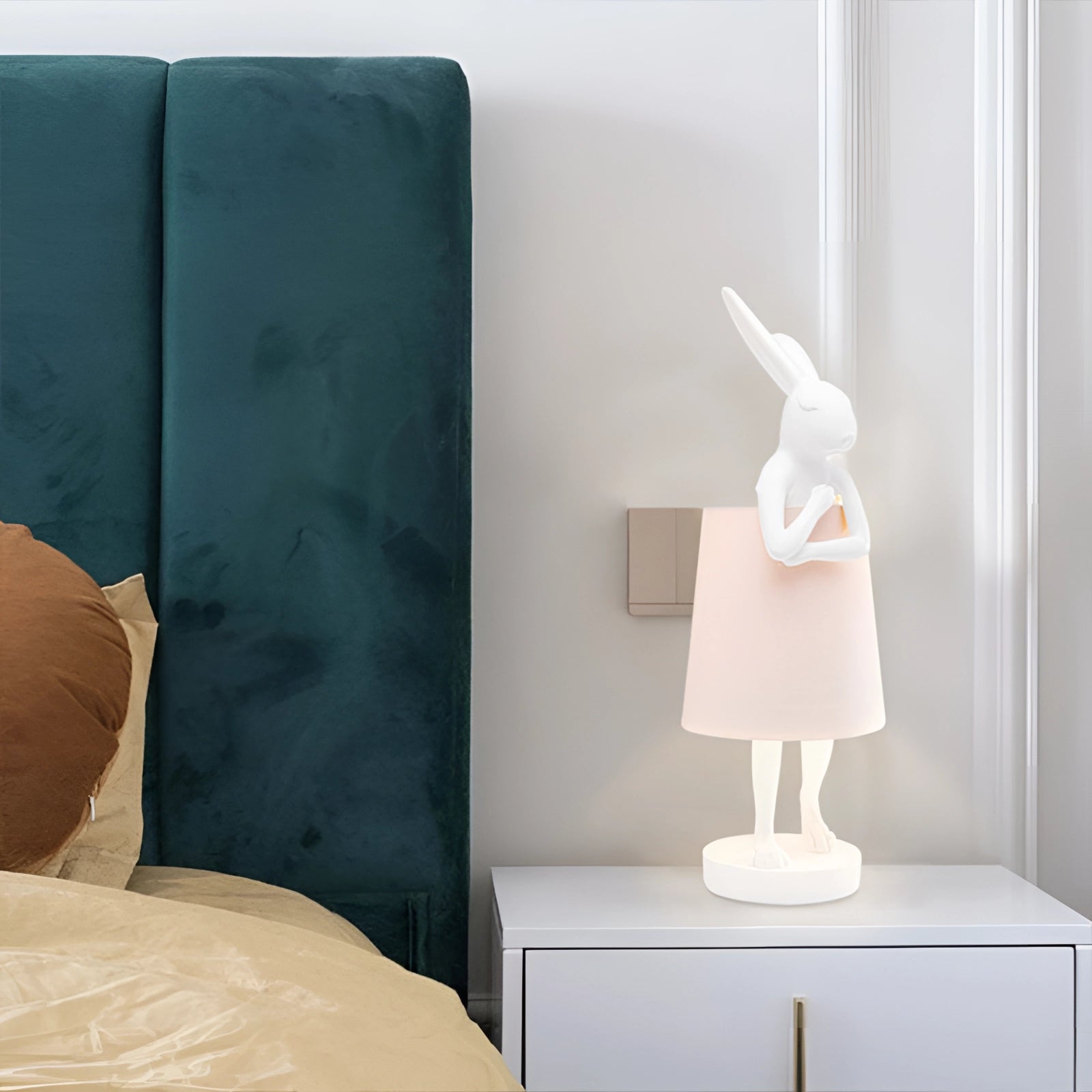 
A luxurious white and gold rabbit lamp positioned on a wooden surface in a stylishly designed room, enhancing the interior decor with its elegant figurine and warm lighting.