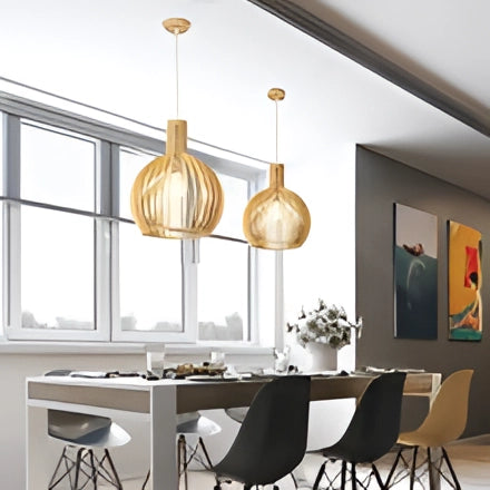 Golden wooden pendant light hanging above a modern dining room table with chairs, surrounded by large windows, indoor plants, and contemporary interior design elements.