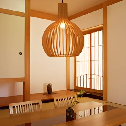 Golden wooden pendant light hanging above a modern dining room table, showcasing warm wood tones and sleek design that complements the hardwood flooring and window in the interior setting.