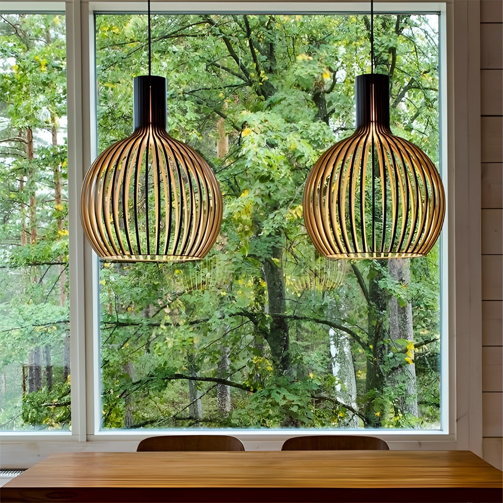 A modern dining room featuring a golden wooden pendant light with a black exterior and wooden interior, measuring 45 cm, hanging above a table. The interior space includes greenery with plants and leaves, complementing the interior design with natural elements and wood accents.