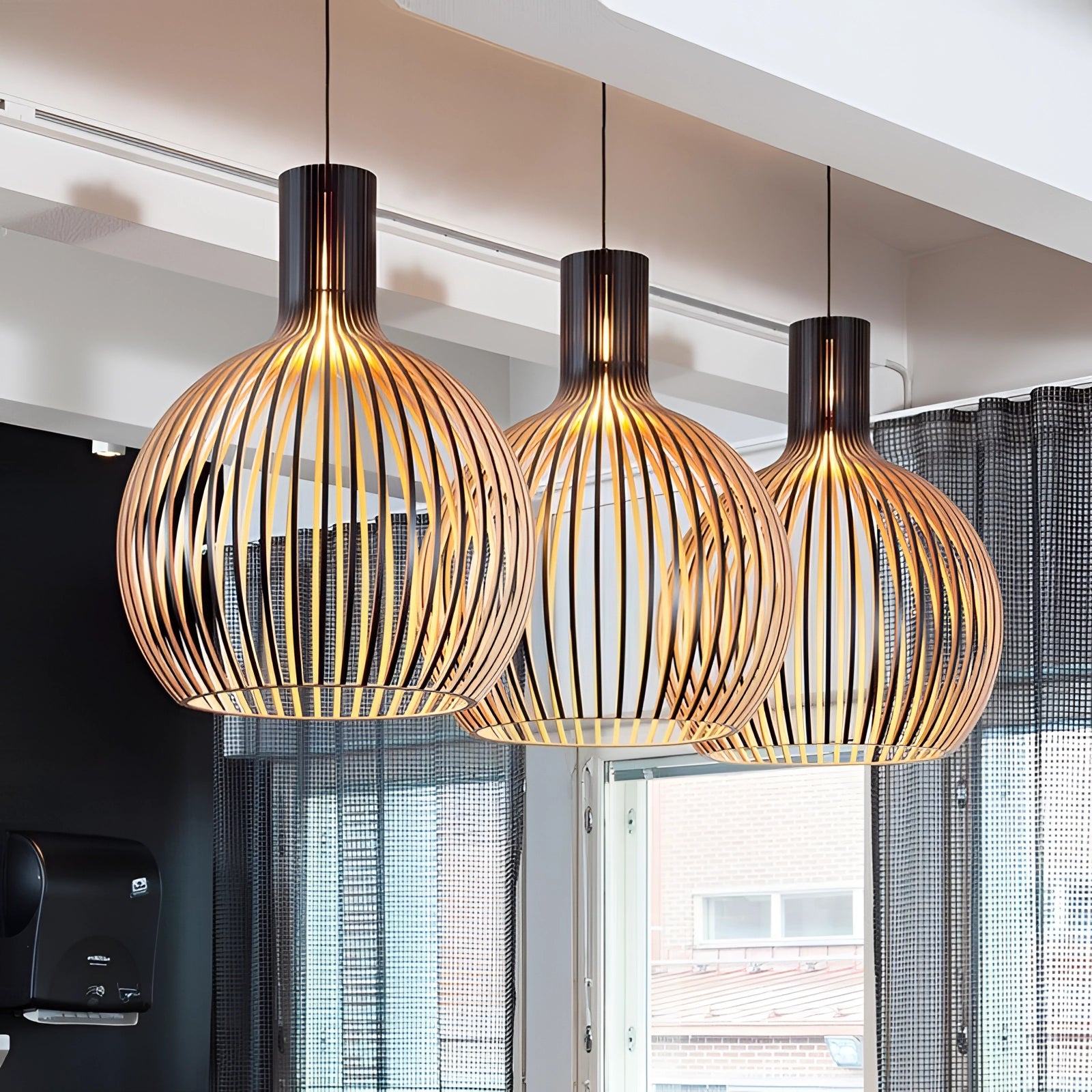 A modern golden wooden pendant light with a rectangular shade, combining elements of wood, textile, and glass, designed to hang from the ceiling as a stylish fixture for a dining room.