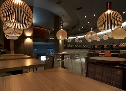 Golden wooden pendant light hanging from the ceiling, illuminating a modern dining room with wooden elements and contemporary interior design.